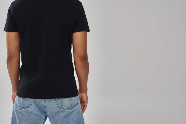 κομψό αφροαμερικάνικο ανδρικό μοντέλο ποζάρει σε μαύρο t-shirt και τζιν, φωτοτυπικός χώρος για διαφήμιση - Φωτογραφία, εικόνα