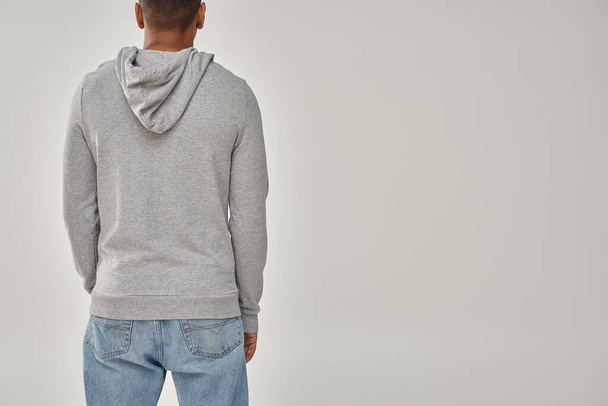 stijlvolle Afro-Amerikaanse man in grijze casual sweatshirt en jeans, kopieer ruimte voor reclame - Foto, afbeelding