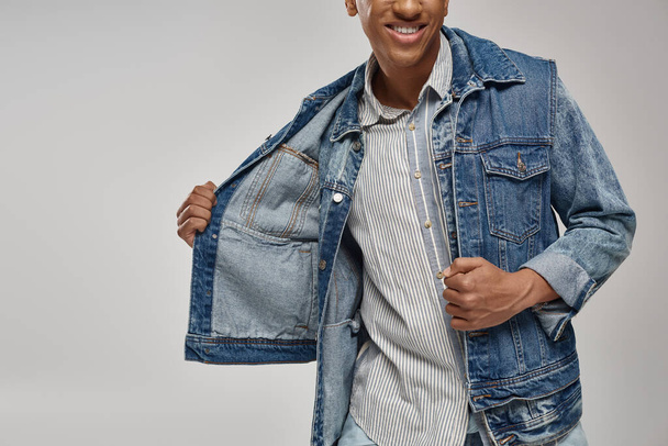 обрезанный вид на стильный африканский американский мужчина модель позирует в модном джинсовом наряде, концепция моды - Фото, изображение