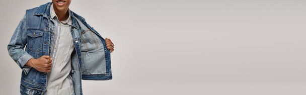 Ausgeschnittene Ansicht eines stilvollen afrikanisch-amerikanischen Mannes, der im trendigen Jeans-Outfit posiert, Modekonzept, Banner - Foto, Bild