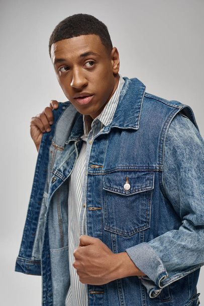 handsome emotional african american man in denim outfit posing on white backdrop, fashion concept - Fotografie, Obrázek