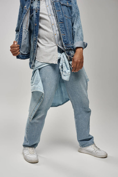 vista cortada do elegante modelo masculino afro-americano posando em roupa de ganga na moda, conceito de moda - Foto, Imagem