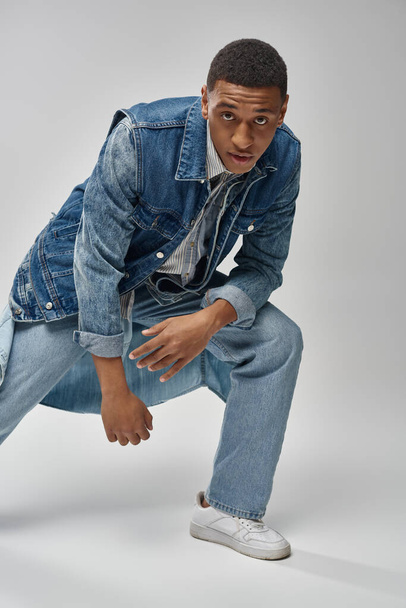 красивий емоційний афроамериканський чоловік в джинсовому вбранні, позує на білому тлі, концепція моди - Фото, зображення