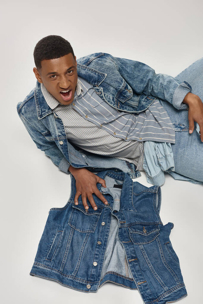 good looking african american man in stylish denim outfit posing in motion, fashion concept - Photo, Image