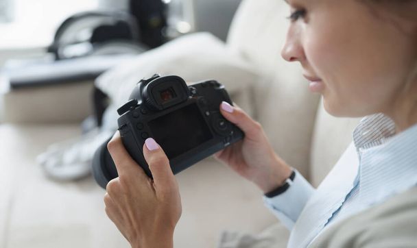 Donna tiene la macchina fotografica professionale nera nelle sue mani. Come diventare fotografo professionista da solo dal concetto di zero - Foto, immagini