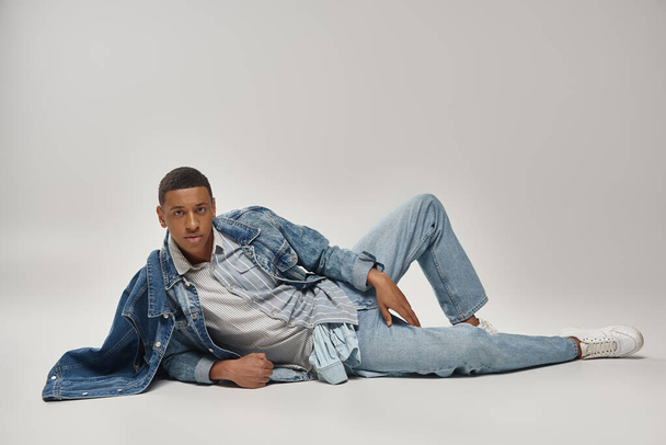 atraente emocional afro-americano homem no elegante traje jeans posando em movimento, conceito de moda - Foto, Imagem