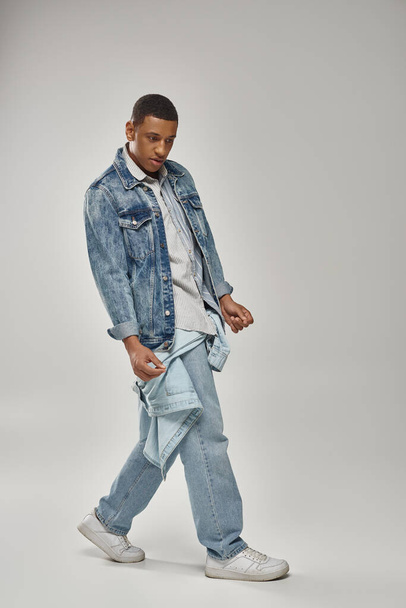 молодий модний афроамериканський чоловік у стильному джинсовому вбранні позує на білому тлі, мода - Фото, зображення