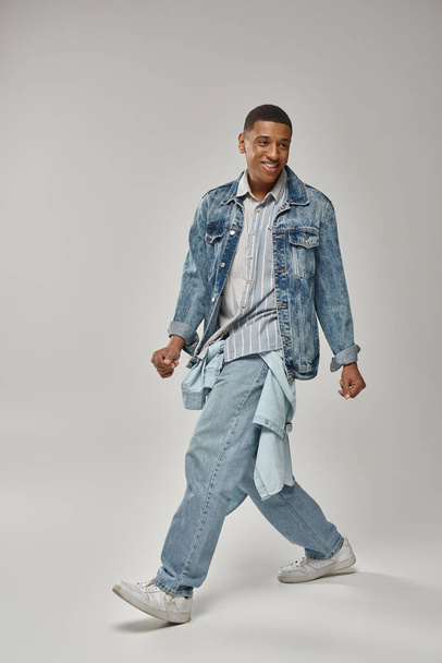 молодой модный африканский американец в стильной джинсовой одежде позирует на белом фоне, мода - Фото, изображение