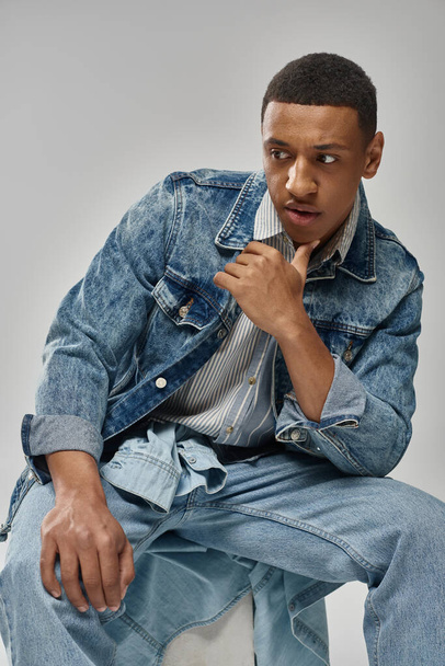 young trendy african american man in stylish denim outfit posing on white backdrop, fashion - Valokuva, kuva