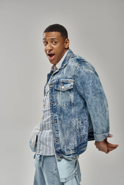 shocked emotional african american man in stylish denim outfit gesturing lively, fashion concept - Photo, Image