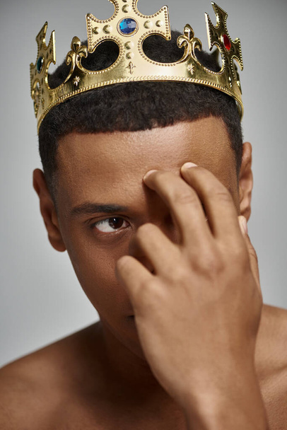 atractivo hombre afroamericano en la corona de oro posando en topless con la mano cerca de la cara, concepto de moda - Foto, imagen