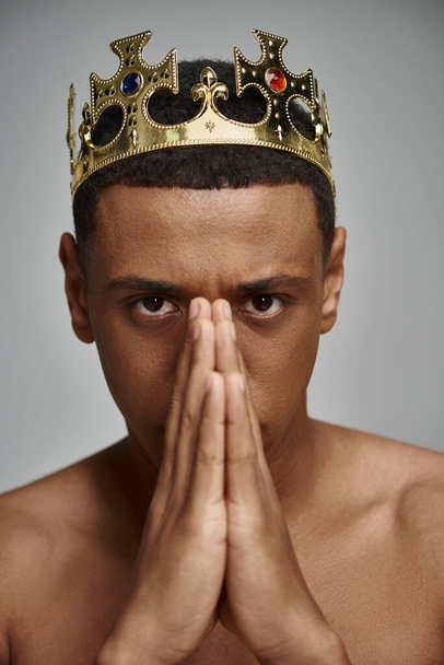 verleidelijke Afrikaanse Amerikaanse man in gouden kroon poseren topless met handen in de buurt van gezicht, mode concept - Foto, afbeelding