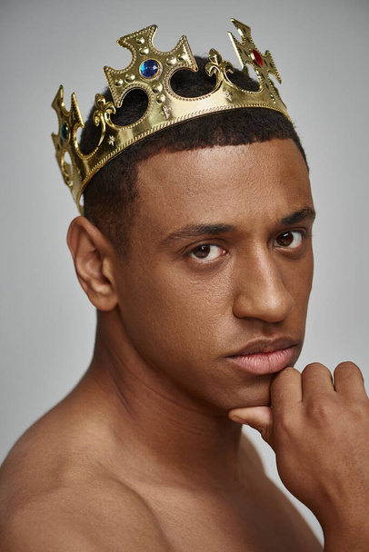 atractivo hombre afroamericano en la corona de oro posando en topless con la mano cerca de la cara, concepto de moda - Foto, Imagen