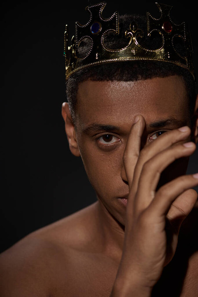 csábító afro-amerikai férfi arany korona pózol félmeztelen kézzel közel arc, divat koncepció - Fotó, kép