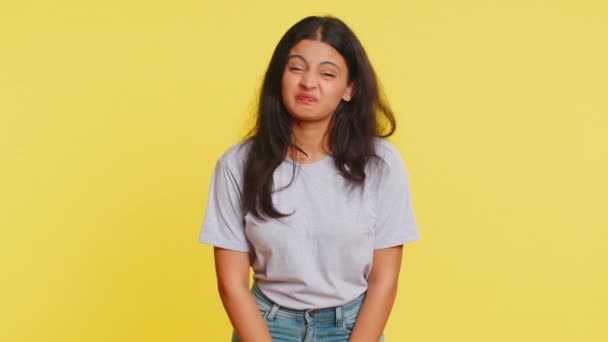 Mujer joven india juguetona mostrando la lengua haciendo caras en la cámara, jugando, bromeando, aping con cara tonta, burlas, intimidación, abuso. alegre divertido árabe chica aislado en amarillo fondo - Metraje, vídeo