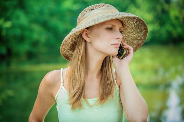 Дівчина в солом'яному капелюсі з телефоном
 - Фото, зображення