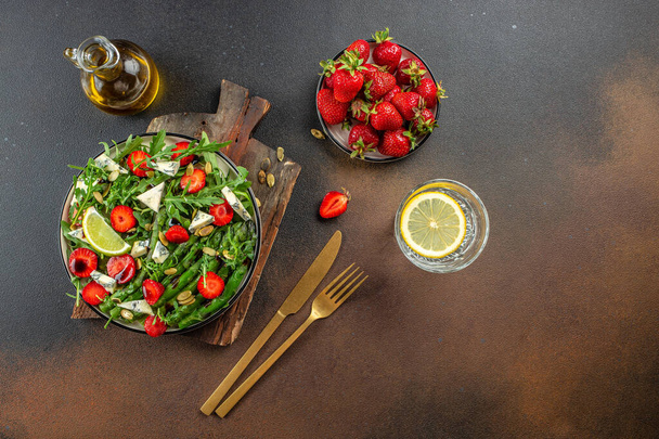 Gesunde grüne Salatblätter, Scheiben frischer Erdbeeren. Konzept einer gesunden und ausgewogenen Ernährung. Platz für Text, Draufsicht. - Foto, Bild
