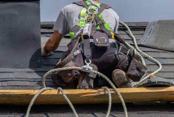 profesjonalny pracownik budowlany człowiek dekarz pracujący nad bezpieczeństwem konserwacji dachu z bezpieczną liną - Zdjęcie, obraz