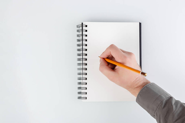 üzleti jegyzettömb, kéz kezében egy ceruza egy fehér háttér közelkép - Fotó, kép