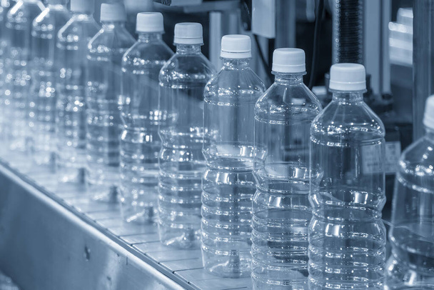 飲料水製造プロセスのハイテク技術。充填プロセスのためのコンベアベルトの空の飲料水ボトル.  - 写真・画像