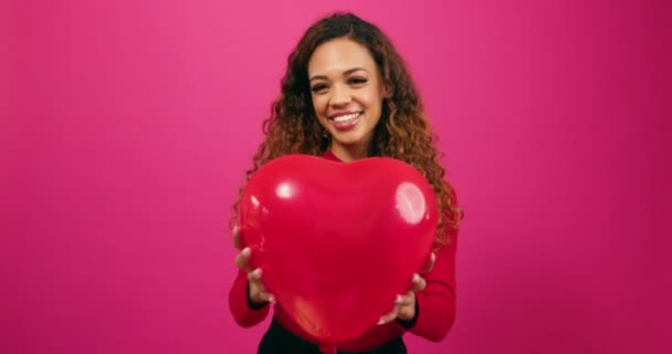 Hermosa mujer joven lanza globo en forma de corazón en el aire riendo, estudio. Imágenes de alta calidad 4k - Metraje, vídeo