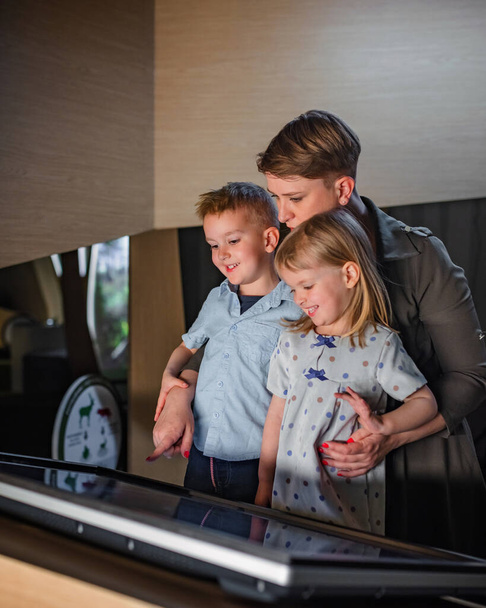 Family visiting a natural history museum, a mother with two children standing in front of a digital interactive display. - Foto, Imagem