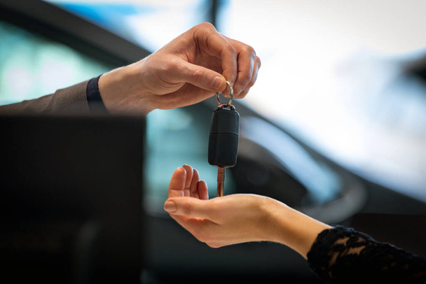 Αγοράστε ένα αυτοκίνητο εννοιολογικό υπόβαθρο. Δώστε ένα νέο αυτοκίνητο κλειδιά σε ένα σαλόνι αυτοκινήτου - Φωτογραφία, εικόνα