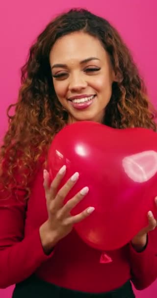 Piękna młoda kobieta trzyma balon w kształcie serca w kierunku kamery, studio. Wysokiej jakości materiał 4k - Materiał filmowy, wideo
