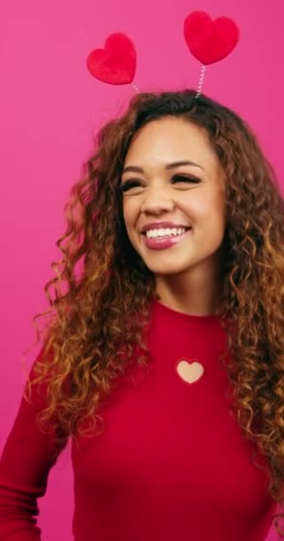 Mutlu genç bir kadın pembe stüdyoda gülüyor, Sevgililer Günü için kalp takıyor. Yüksek kalite 4k görüntü - Video, Çekim