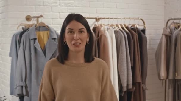 Medium POV toma de la joven estilista de moda femenina caucásica hablando en cámara mientras hace compras en boutique de diseño de lujo con ropa y accesorios de lujo - Metraje, vídeo
