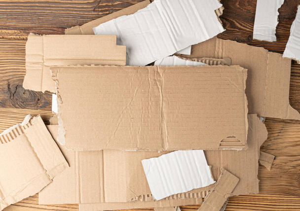 Kawałki kartonu Pile teksturowane tło, Kawałek kartonu z miejsca kopiowania, Tapety papieru Ripped Kraft, Brown Wrapping Vintage papieru na tle drewna rustykalnego - Zdjęcie, obraz