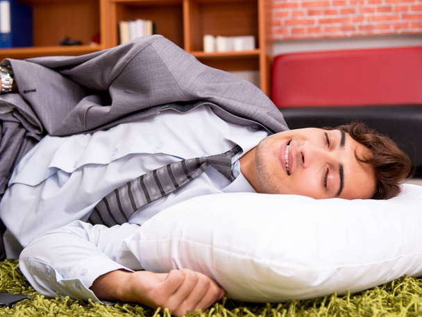 Молодий працівник спить на підлозі в офісі - Фото, зображення