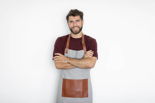 Vrolijke man barista barman in schort poseren met gekruiste gevouwen armen, glimlachen op camera geïsoleerd op witte achtergrond.. Small business startup concept - Foto, afbeelding