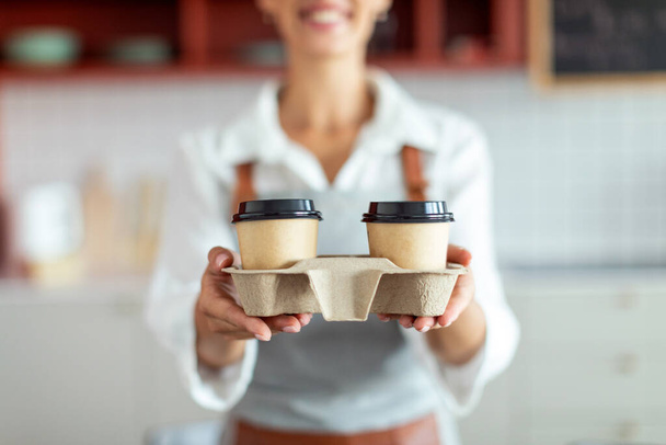 Обрізаний знімок жіночої бариста тримає тримач з гарячими виносними напоями в інтер'єрі кафе, впритул. Концепція малого бізнесу - Фото, зображення