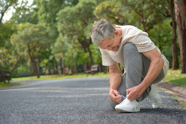 靴ひもを結ぶ老人は運動の準備をします高齢者の転倒の危険を防ぐという概念 - 写真・画像