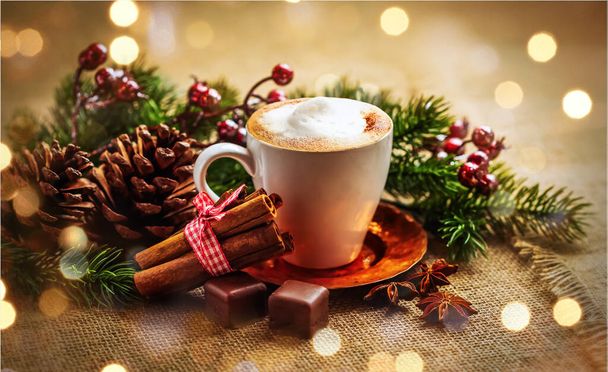 A cup of cappuccino on a copper saucer and cinnamon on a background of Christmas decorations - Photo, Image
