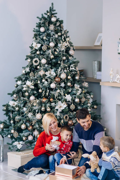 Счастливого Рождества! счастливая семья мать отец и ребенок с волшебным даром возле дерева
 - Фото, изображение