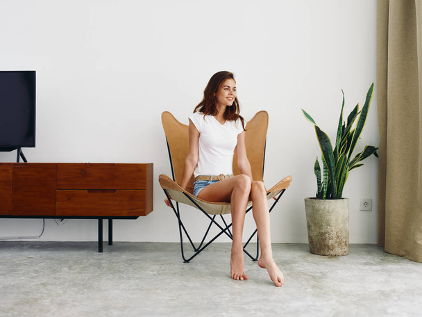 vrouw zitten in lederen fauteuil glimlach met tanden Lifestyle, ontspannen thuis stijlvolle moderne interieur met witte muren, kopiëren ruimte. Hoge kwaliteit foto - Foto, afbeelding
