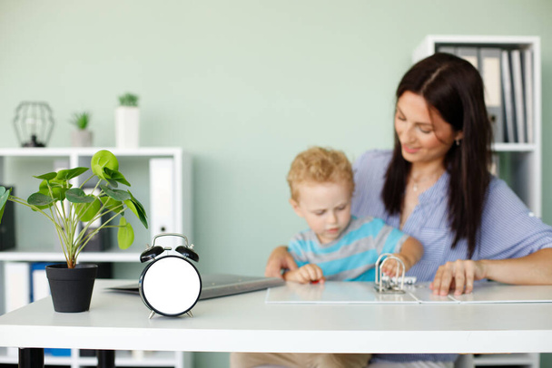 horloge maquette sur fond de travail femme avec un enfant - Photo, image