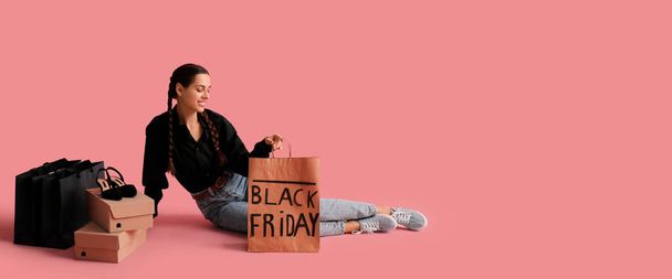 Beautiful young woman with shopping bags and cardboard boxes on pink background with space for text. Black Friday sale - Photo, Image