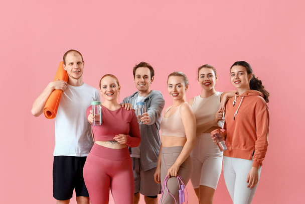Grupo de jóvenes deportistas con equipamiento sobre fondo rosa - Foto, imagen