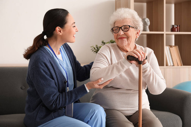 Seniorin mit Stock und Pflegerin zu Hause - Foto, Bild