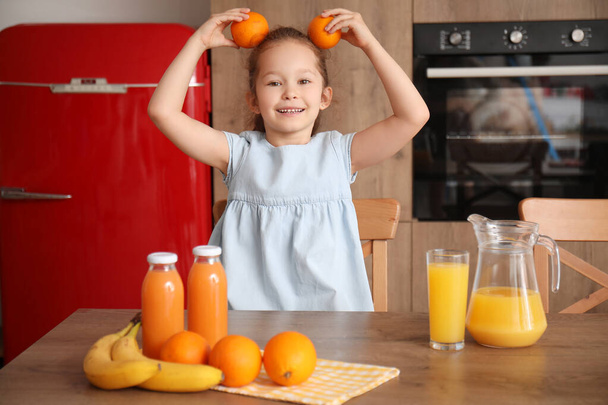 Niña divertida con naranjas en la cocina - Foto, imagen