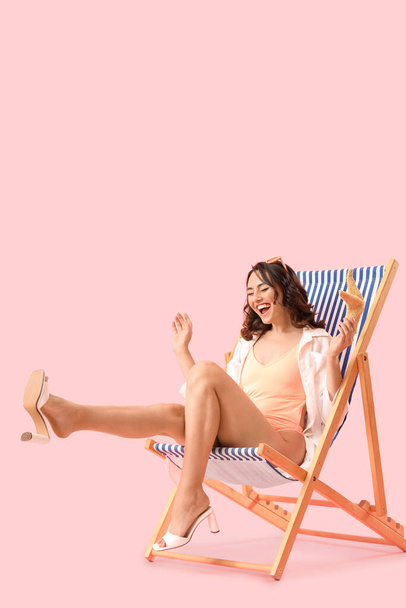 Молода жінка з зіркою в стільці на рожевому фоні - Фото, зображення