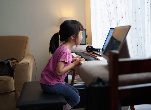 Asian Girl Kid сосредоточилась на онлайн-занятиях по игре на фортепиано. - Фото, изображение