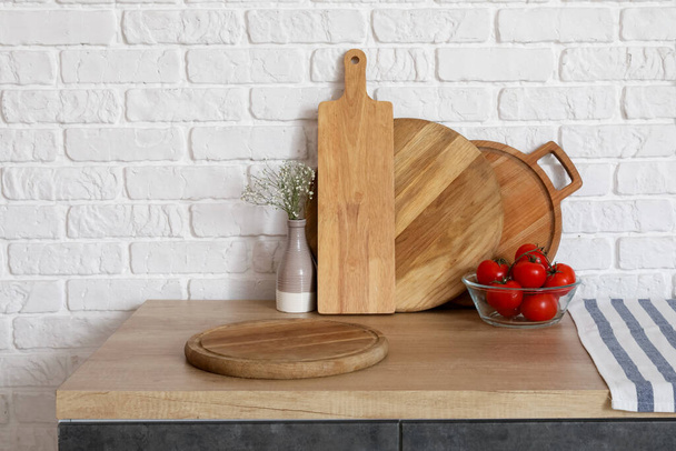 Wooden counter with cutting boards, fresh tomatoes and vase - Photo, Image
