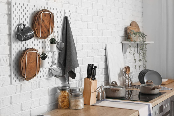 Pegboard s řezacími deskami a nádobím na dřevěných pultech v interiéru moderní kuchyně - Fotografie, Obrázek
