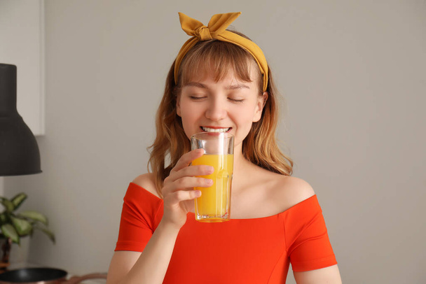 Νεαρή γυναίκα πίνει χυμό πορτοκαλιού στην κουζίνα, κοντινό πλάνο - Φωτογραφία, εικόνα
