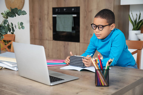 Pequeño niño afroamericano estudiando en línea con el ordenador portátil en la cocina - Foto, Imagen