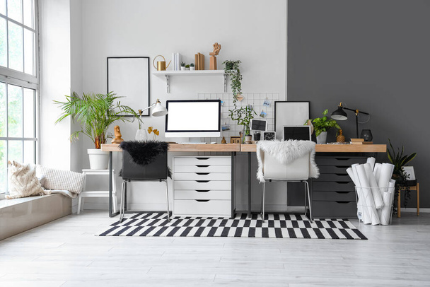 Интерьер современного офиса с рабочими местами и комнатными растениями - Фото, изображение